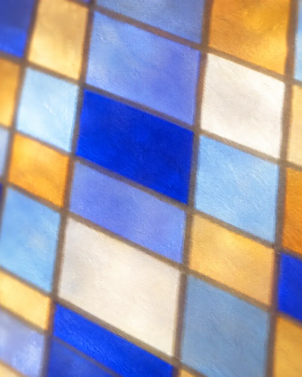 Close-up of stained-glass tiles in Klein blue, amber and clear glass, set in a grid of thin leading